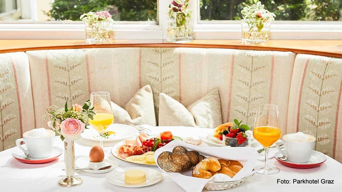 Gedeckter Frühstückstisch im Parkhotel Graz mit Gebäck, Ei, Orangensaft, Cappuccino, Wurst und Käseteller
