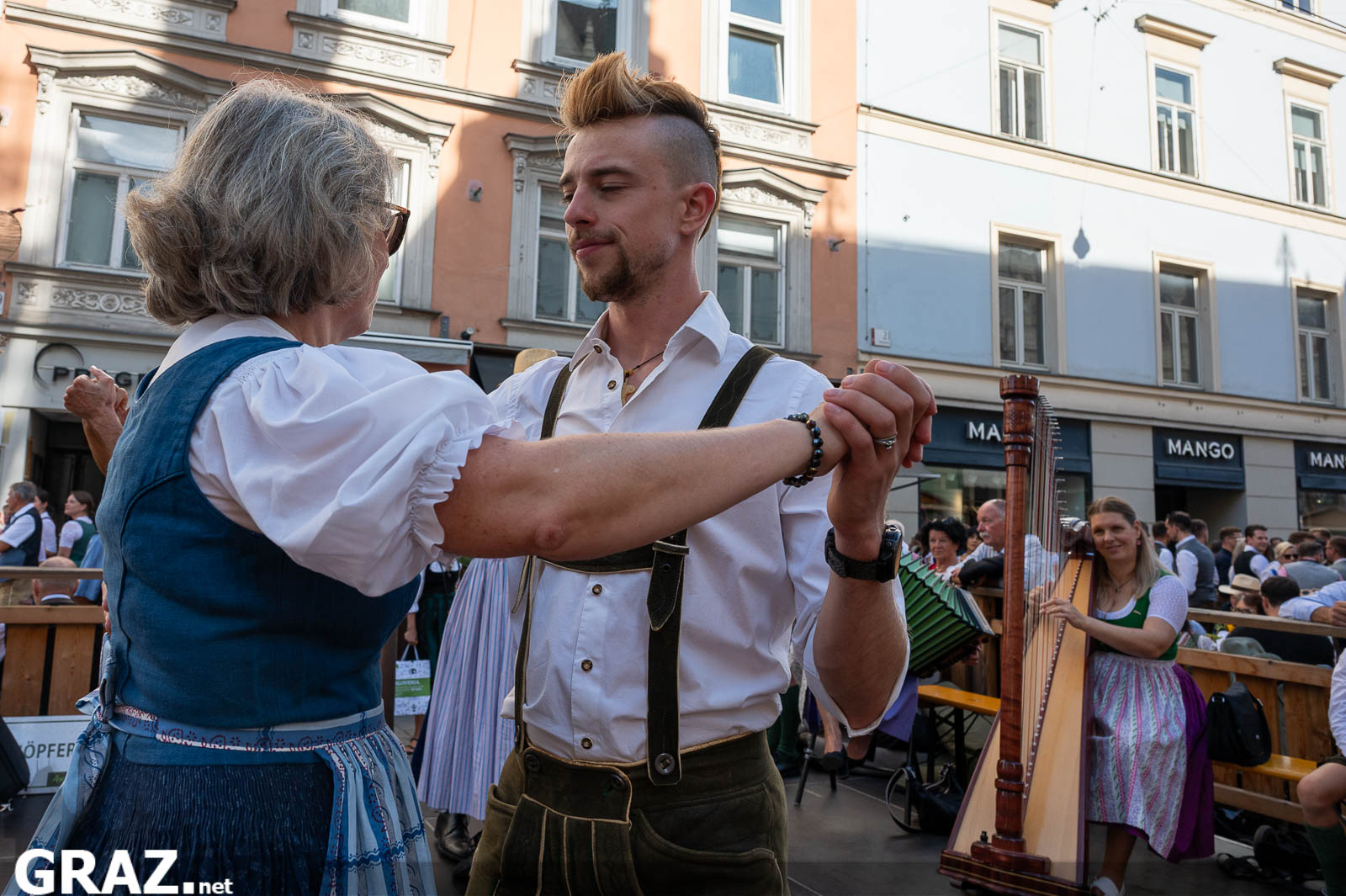 Junger Mann tanzt mit einer älteren Frau in Tracht