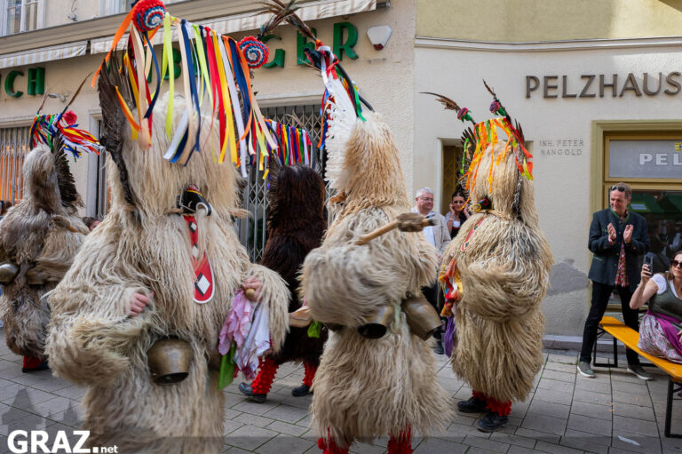 Maskierte Darstellende mit bunten Bändern beim Festzug