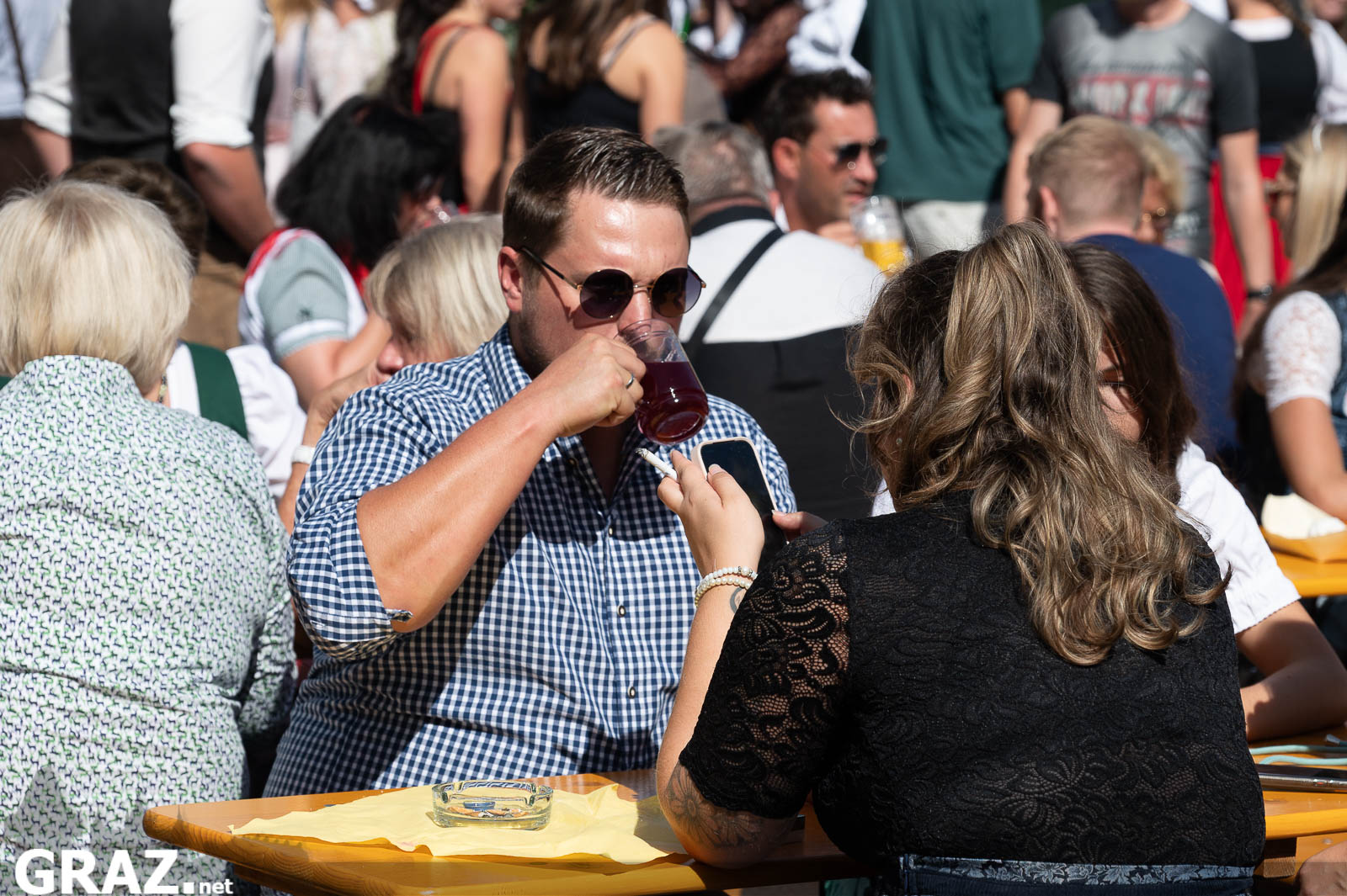 Gäste sitzen an einem Tisch mitten im Festivaltrubel