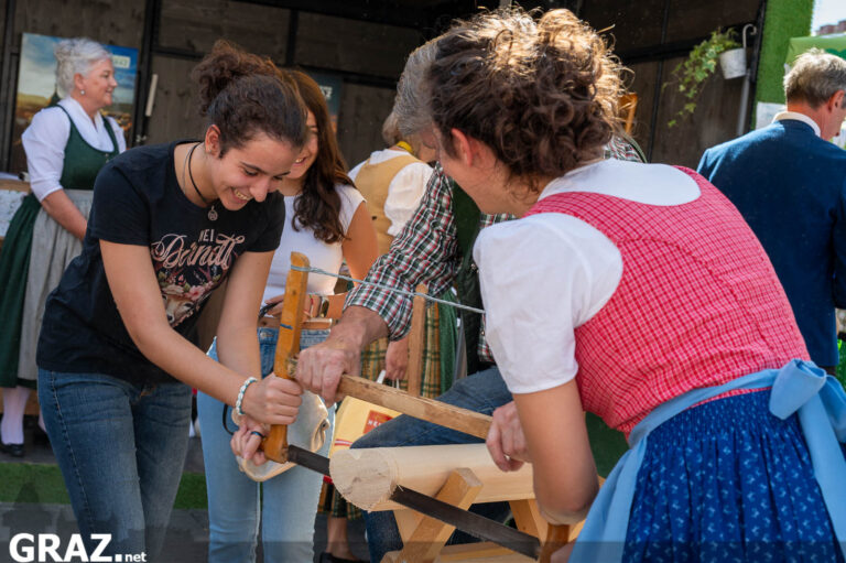 Besucher:innen probieren eine handwerkliche Tätigkeit mit Holz aus
