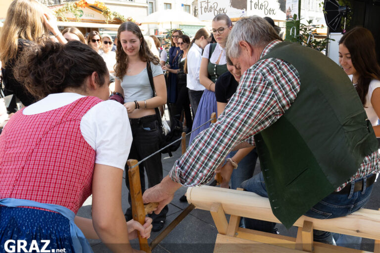 Teilnehmende arbeiten gemeinsam an einem Holzstück