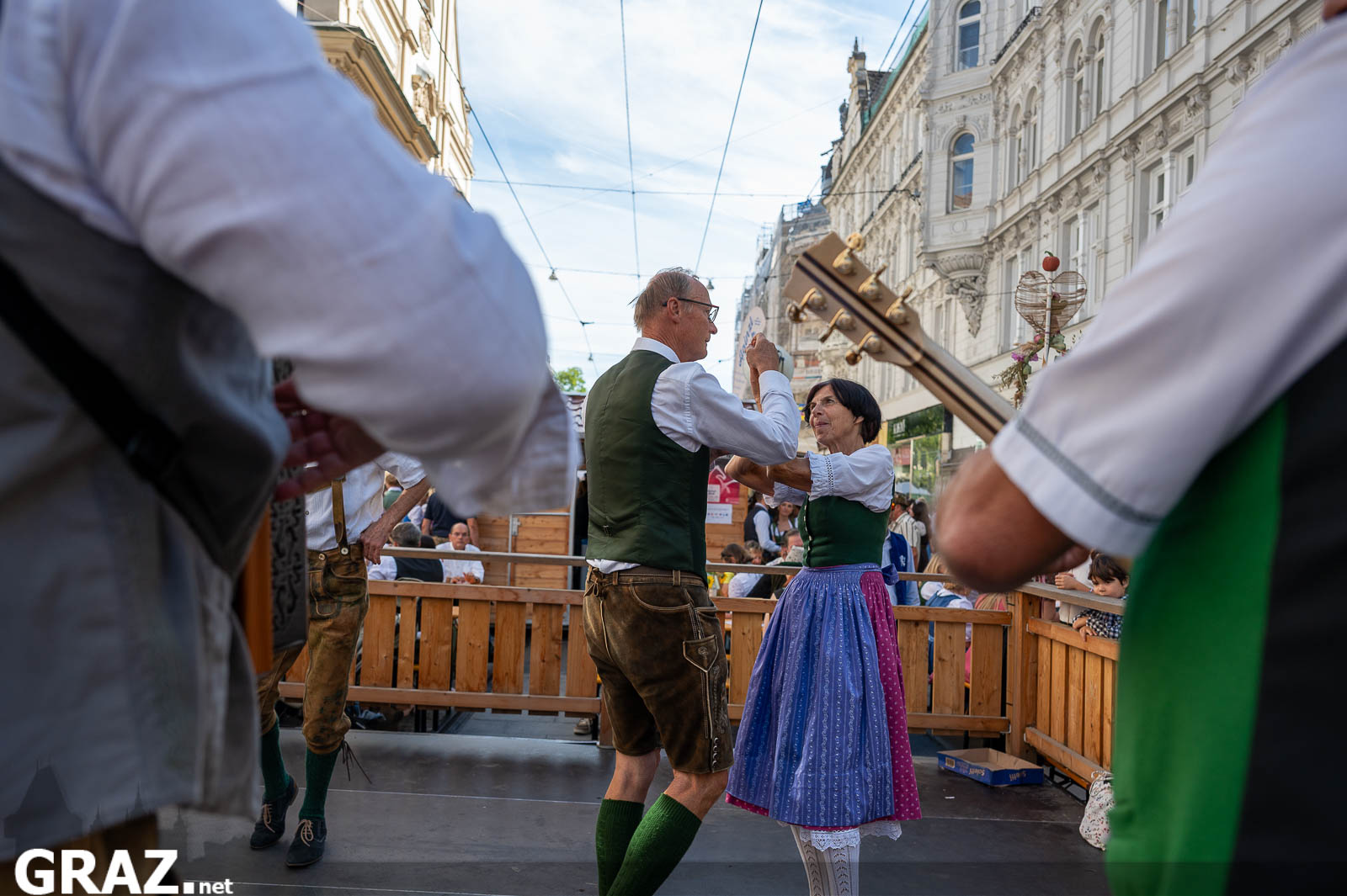 Volkstanz auf der Bühne, von Musizierenden eingerahmt