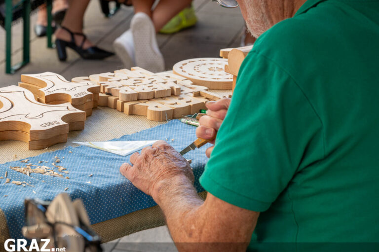 Handwerker bearbeitet Holzfiguren am Stand