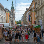 Menschen in Tracht und Alltagskleidung in der Grazer Herrengasse