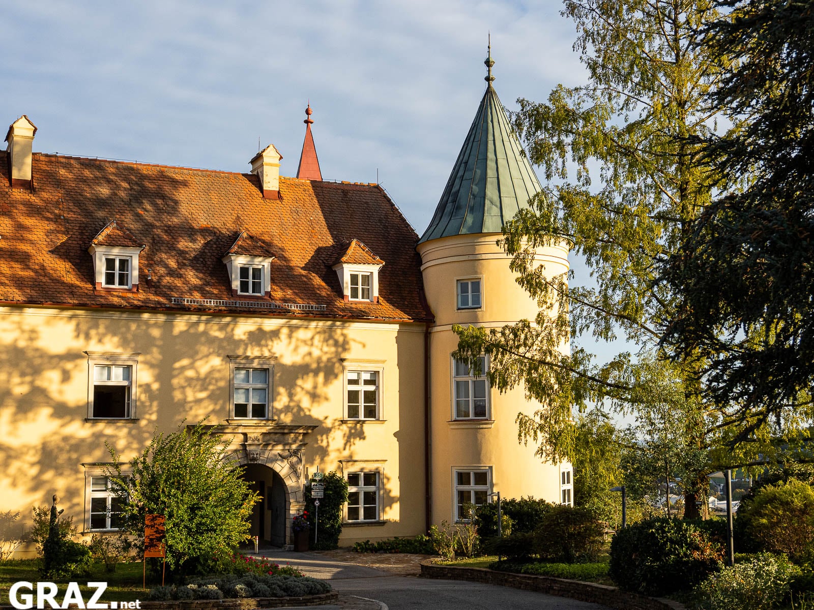 Sonnenbeschienene Fassade von Schloss St. Martin mit rundem Eckturm und herbstlichen Bäumen