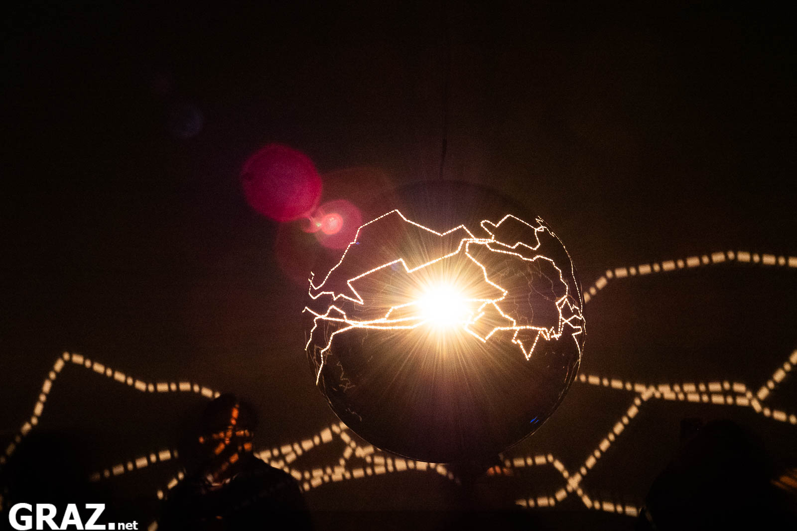 Licht dringt durch die geschwungenen Öffnungen der hängenden Kugel von Helga Griffiths’ „Migratory Senses“ in Schloss Eggenberg.