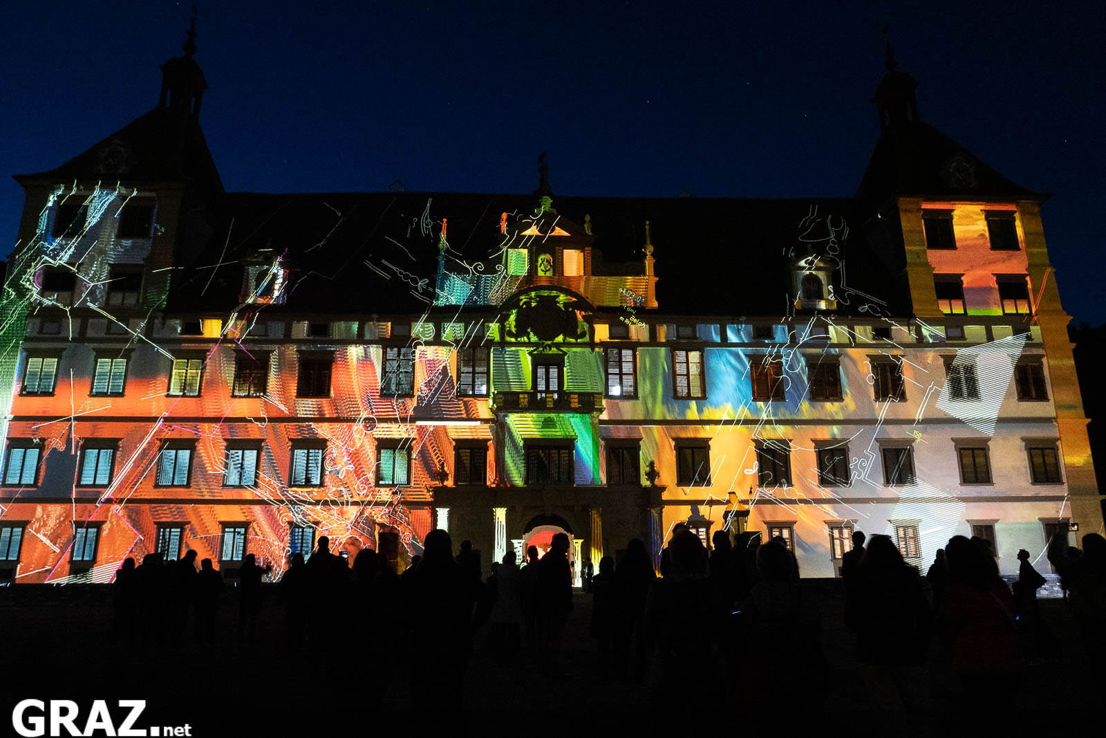 Orange, blaue und grüne Bildflächen von Daniel Rossas „Kadenzen“ überziehen die Schlossfassade bei Klanglicht Graz 2026.