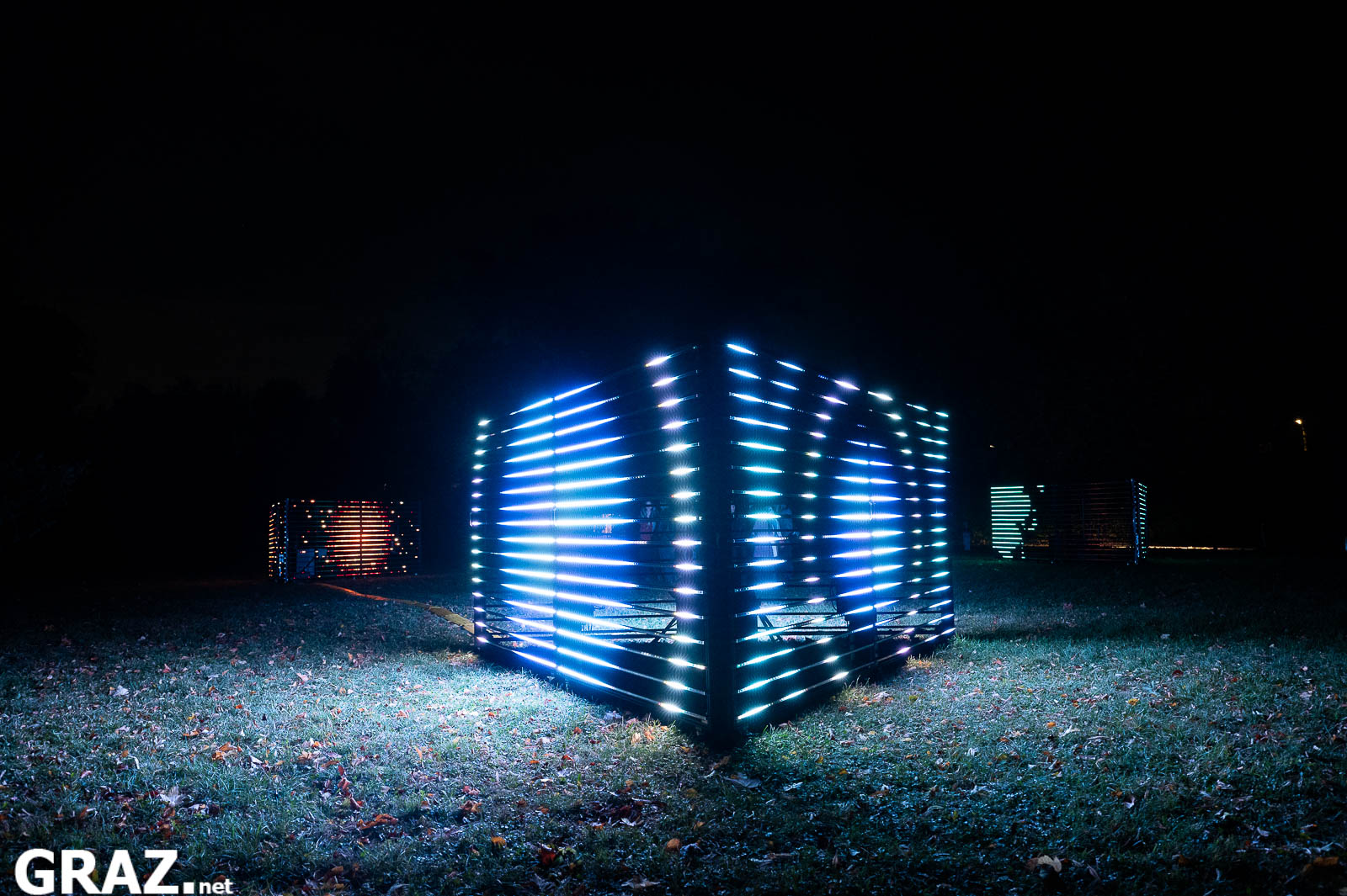 Seitlicher Blick auf einen blau-weiß leuchtenden Kubus aus „Prism“ von Studierenden der FH JOANNEUM und Kunstuniversität Graz.