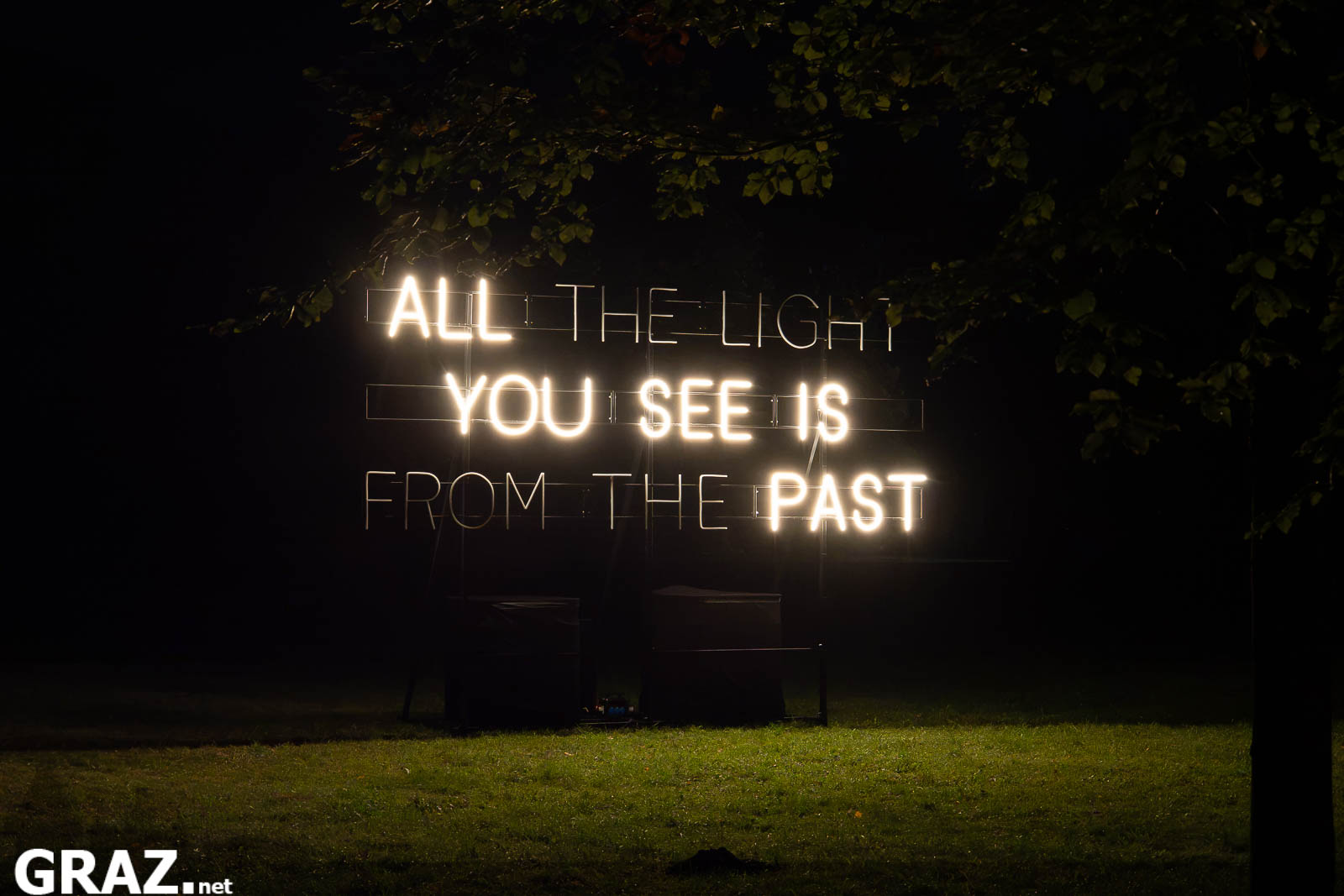 Alicia Eggerts leuchtender Schriftzug „All the light you see“ auf einer Wiese im Schlosspark Eggenberg.