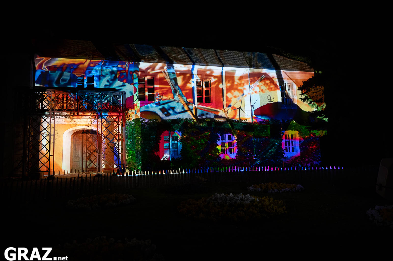 Bunte Bildfragmente aus Zeineb Kaabis „Energy in Time“ überziehen ein Gebäude im Schlosspark Eggenberg.