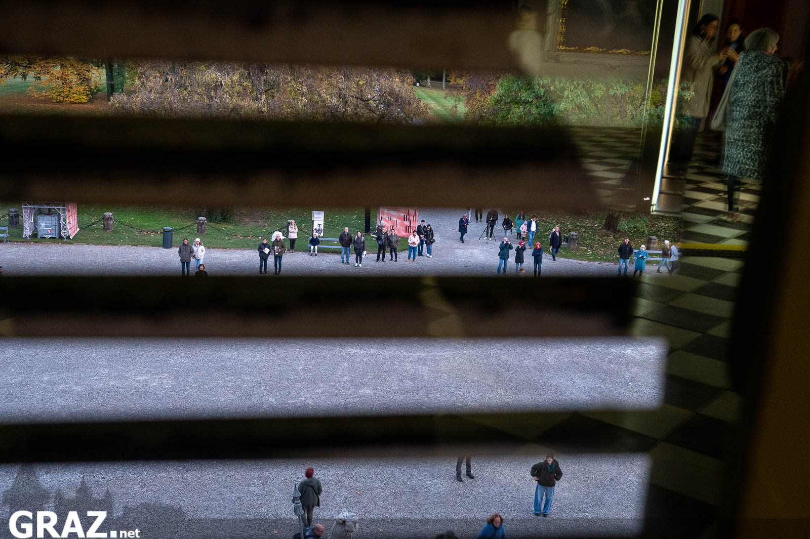 Spiegelungen des Schlossparks und von Gästen in einem Innenraum von Schloss Eggenberg bei Klanglicht Graz 2026.